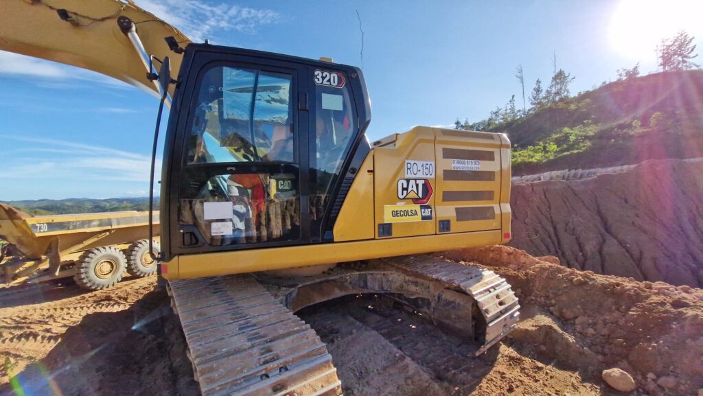 Excavadora CAT 320 operando en terreno montañoso bajo el sol, utilizada en obra activa de construcción pesada.