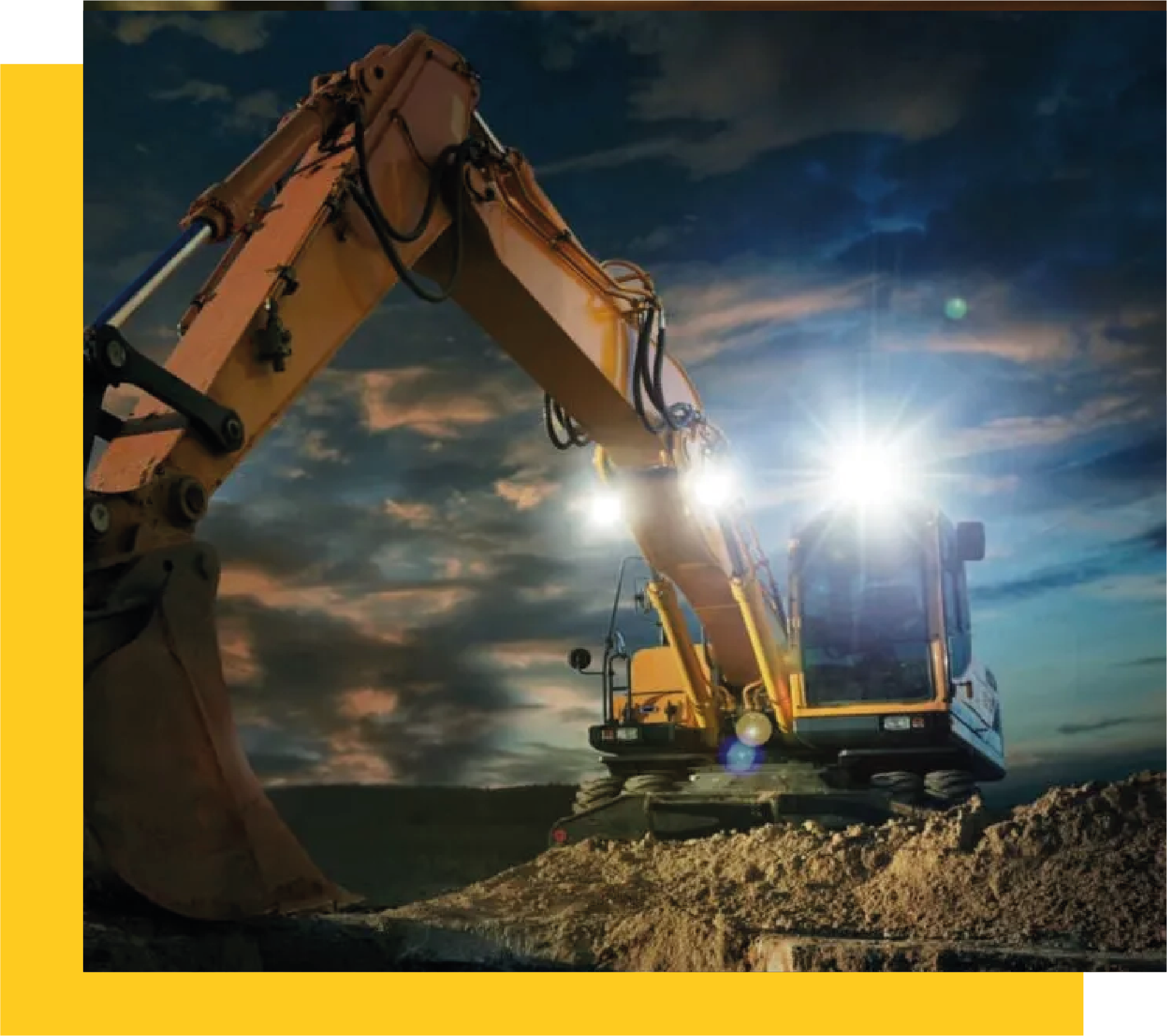 Excavadora Caterpillar trabajando al anochecer con luces encendidas sobre un terreno de construcción.