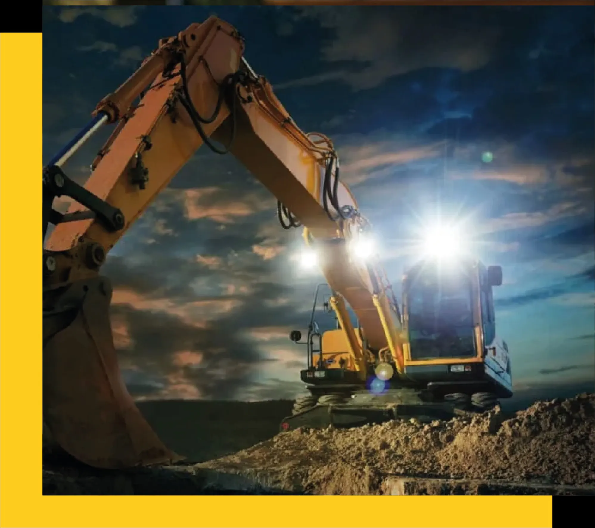 Excavadora Caterpillar trabajando al anochecer con luces encendidas sobre un terreno de construcción.
