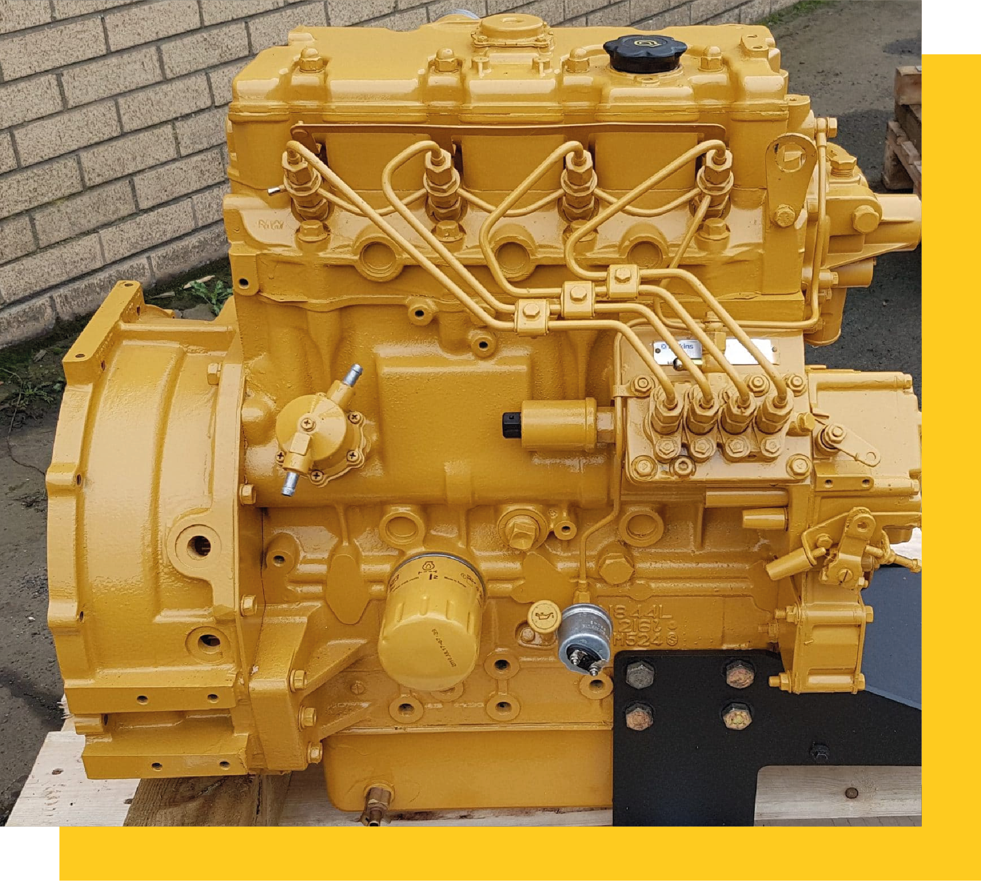 Motor Caterpillar reconstruido y pintado de amarillo, sobre plataforma de madera.