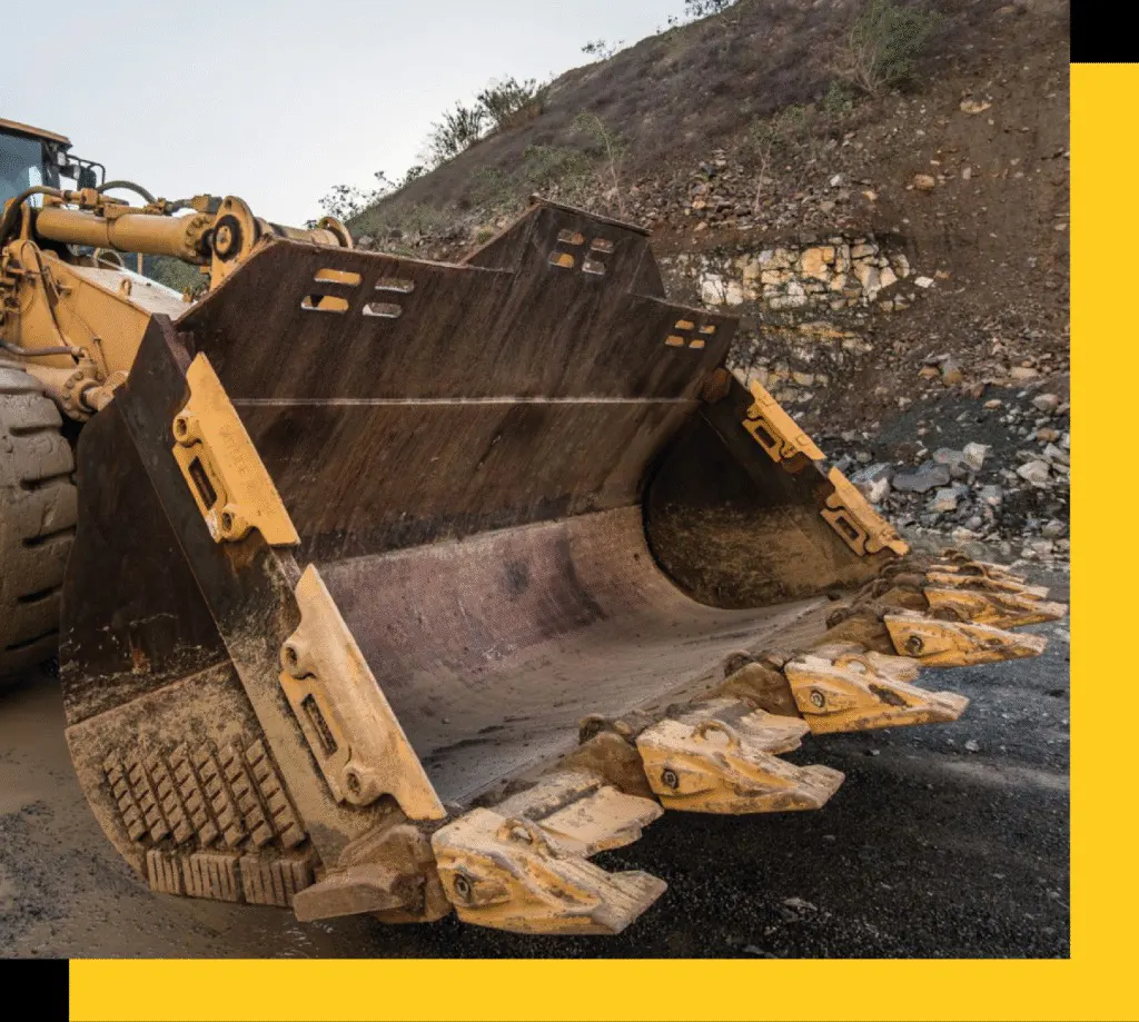 Cuchara de excavadora Caterpillar equipada con repuestos resistentes, en una zona de explotación minera.