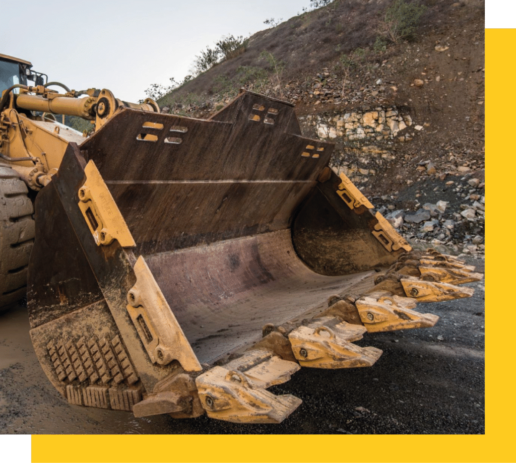 Cuchara de excavadora Caterpillar equipada con repuestos resistentes, en una zona de explotación minera.