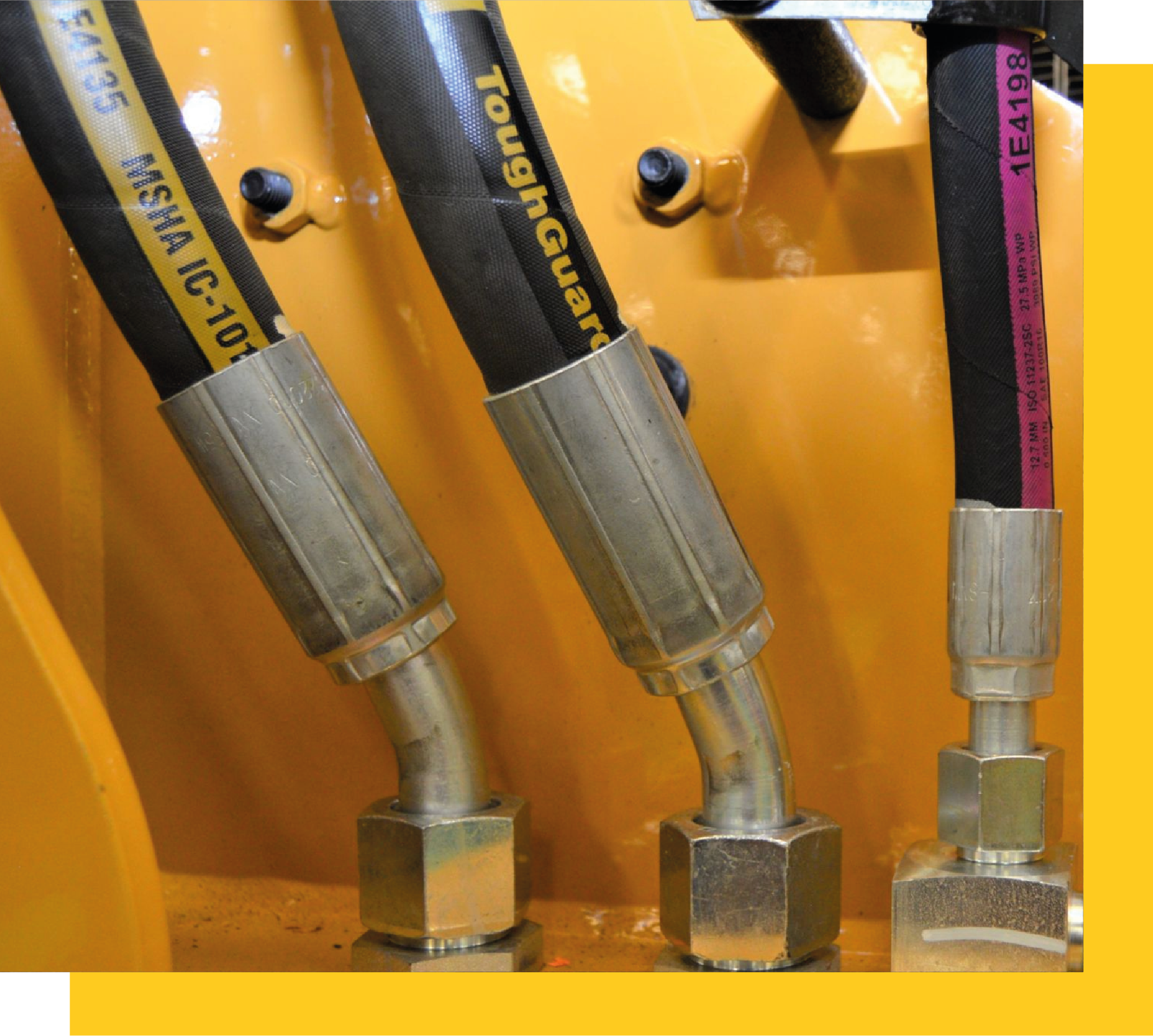 Mangueras hidráulicas Caterpillar con conectores metálicos, instaladas en maquinaria pesada.