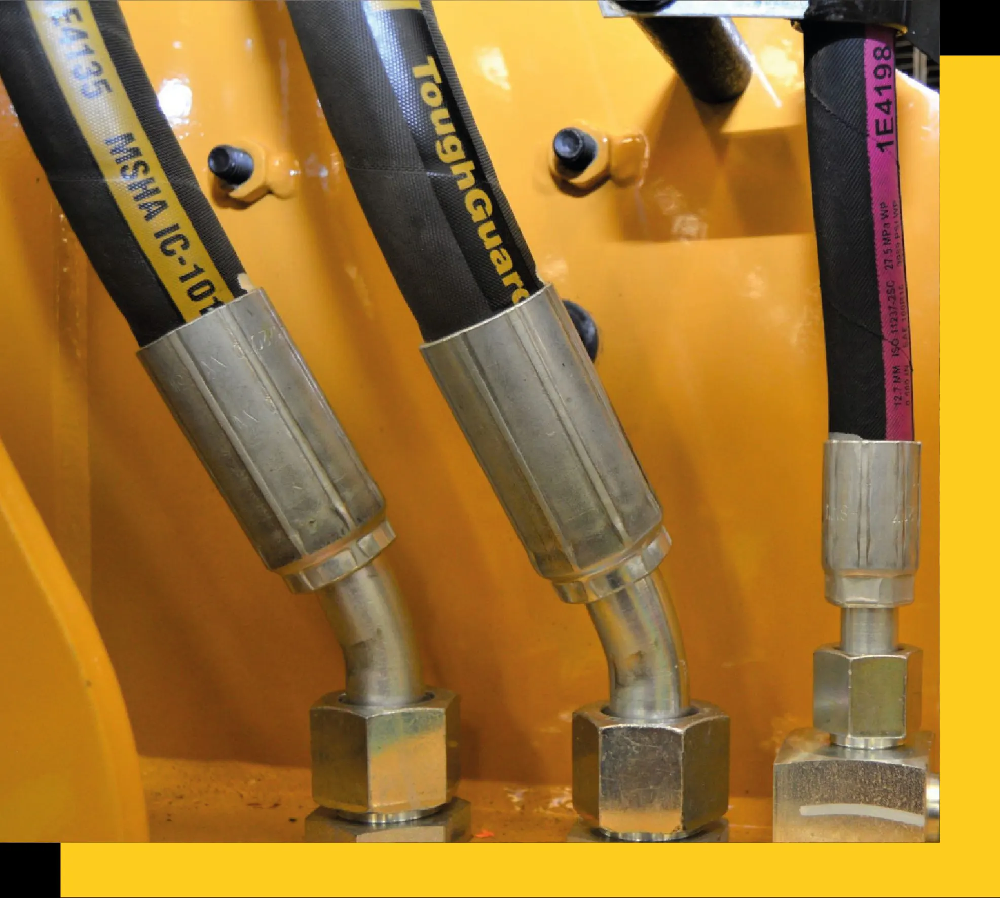 Mangueras hidráulicas Caterpillar con conectores metálicos, instaladas en maquinaria pesada.